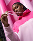 Person wearing a pink and white hoodie with a pink background