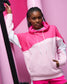 Person wearing a pink and white hoodie against a pink background