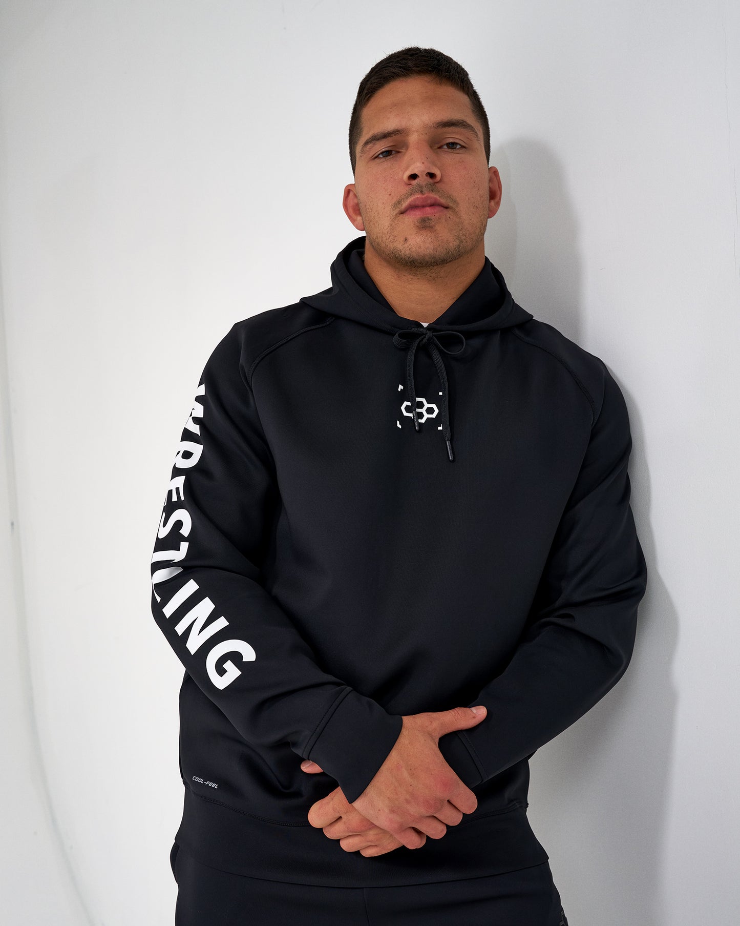 Man wearing a black hoodie with 'WRESTLING' text on a white background