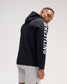 Rear three-quarter view of a male athlete wearing the black RUDIS Wrestling COOL-FEEL Hoodie, highlighting the hood and WRESTLING sleeve graphic.