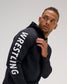 Male athlete wearing the black RUDIS Wrestling COOL-FEEL Hoodie, featuring a close view of the bold white WRESTLING sleeve graphic.