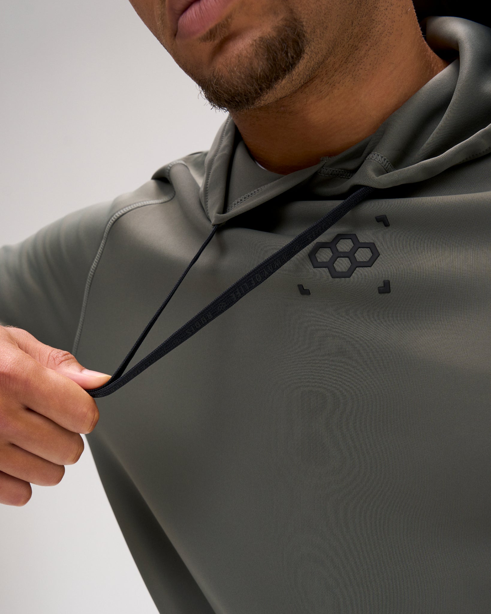 Close-up of the dark olive RUDIS Wrestling COOL-FEEL Hoodie showing the black drawcord, performance fabric, and RUDIS chest mark.