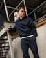 Person wearing a dark hoodie and pants standing on a metal staircase.