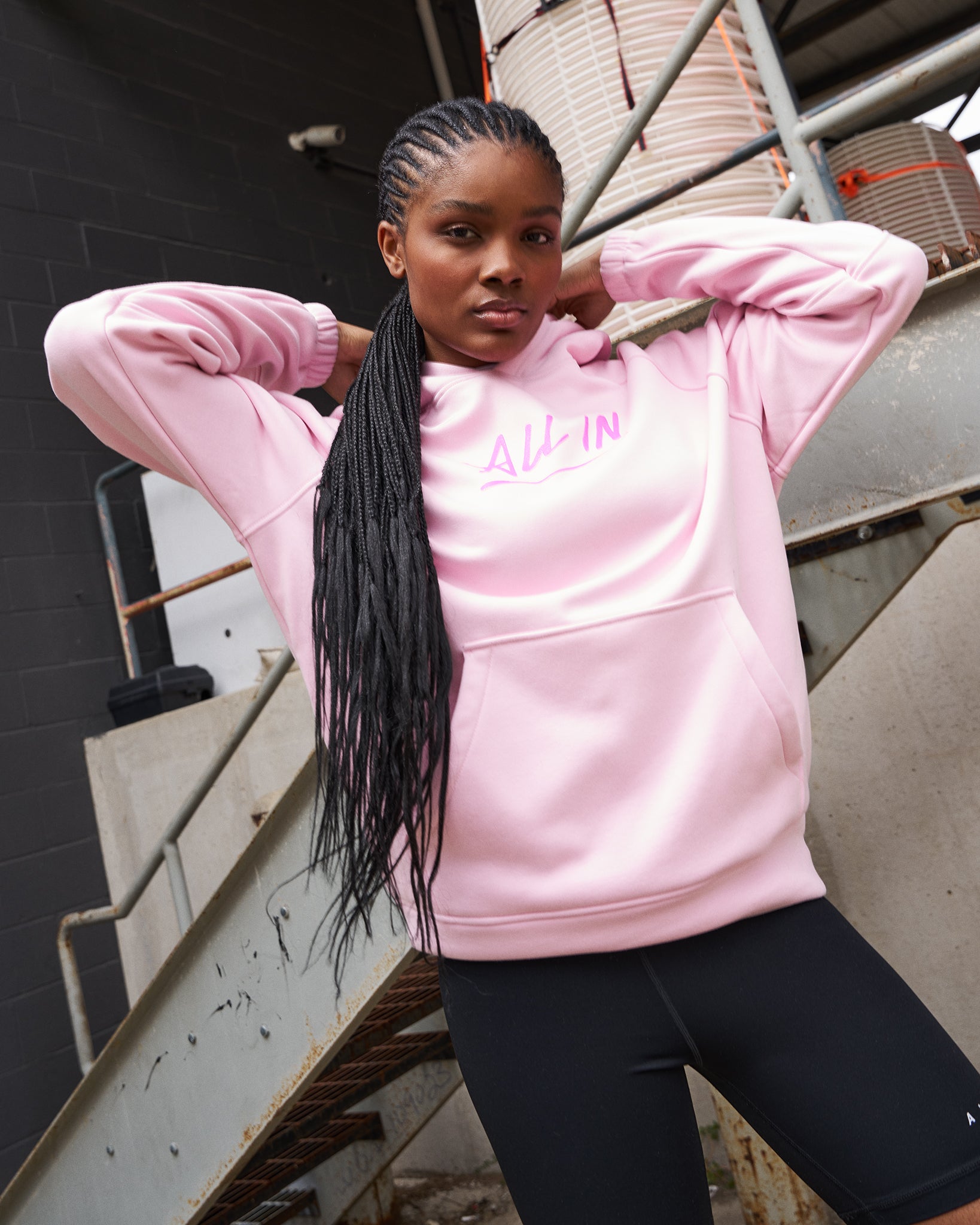 Person wearing a pink hoodie with text, standing outdoors.