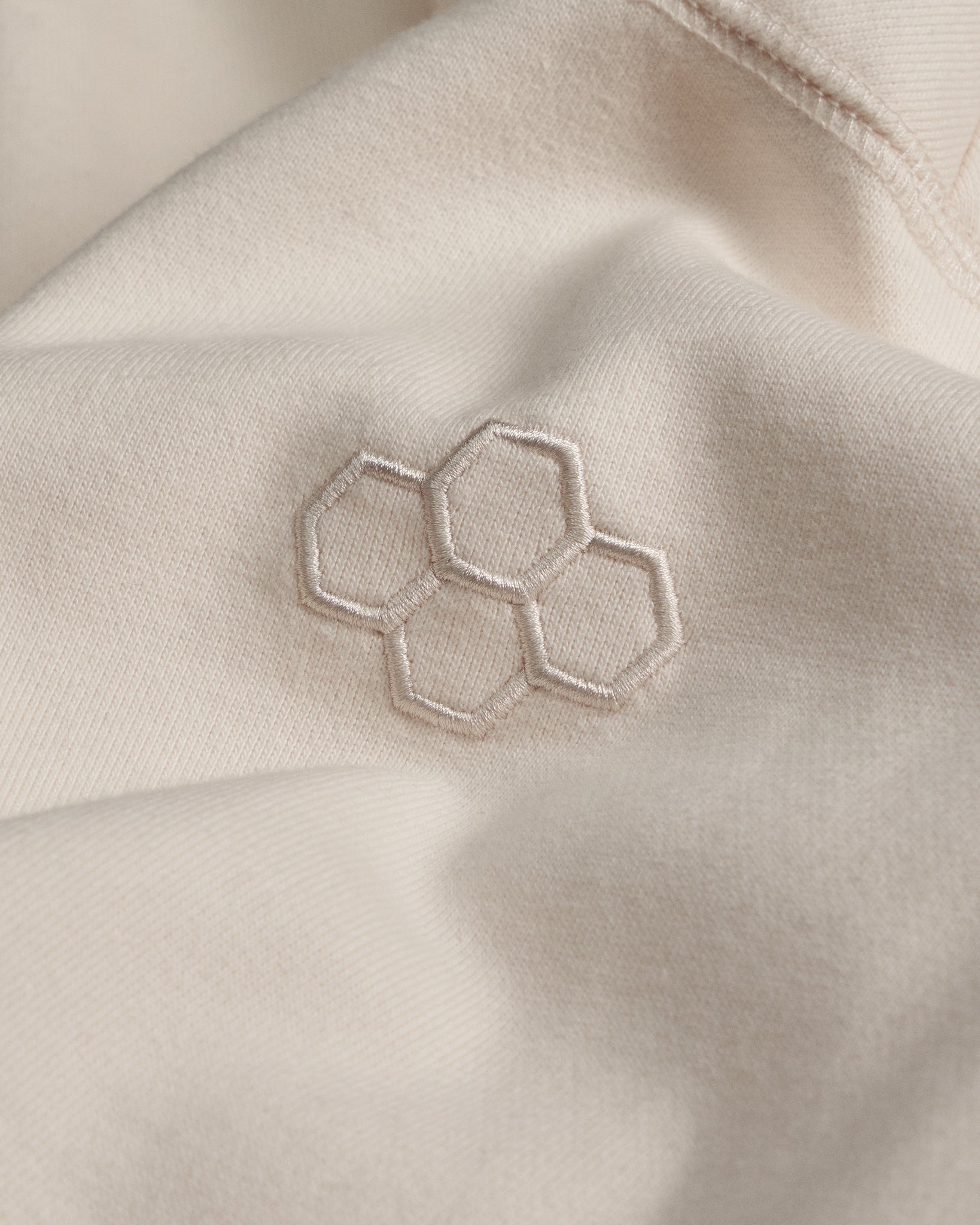 Close-up of beige fabric with a geometric hexagonal pattern embroidered on it.