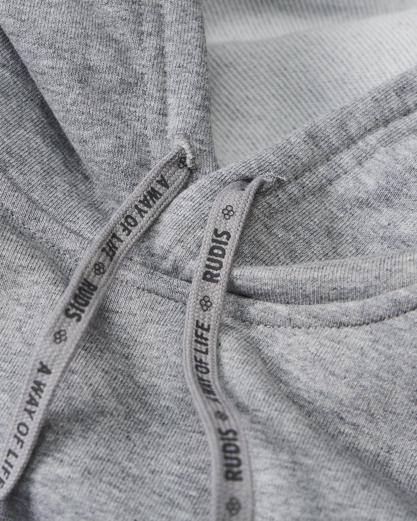 Close-up of gray fabric with 'Rudis' branding on a tag.