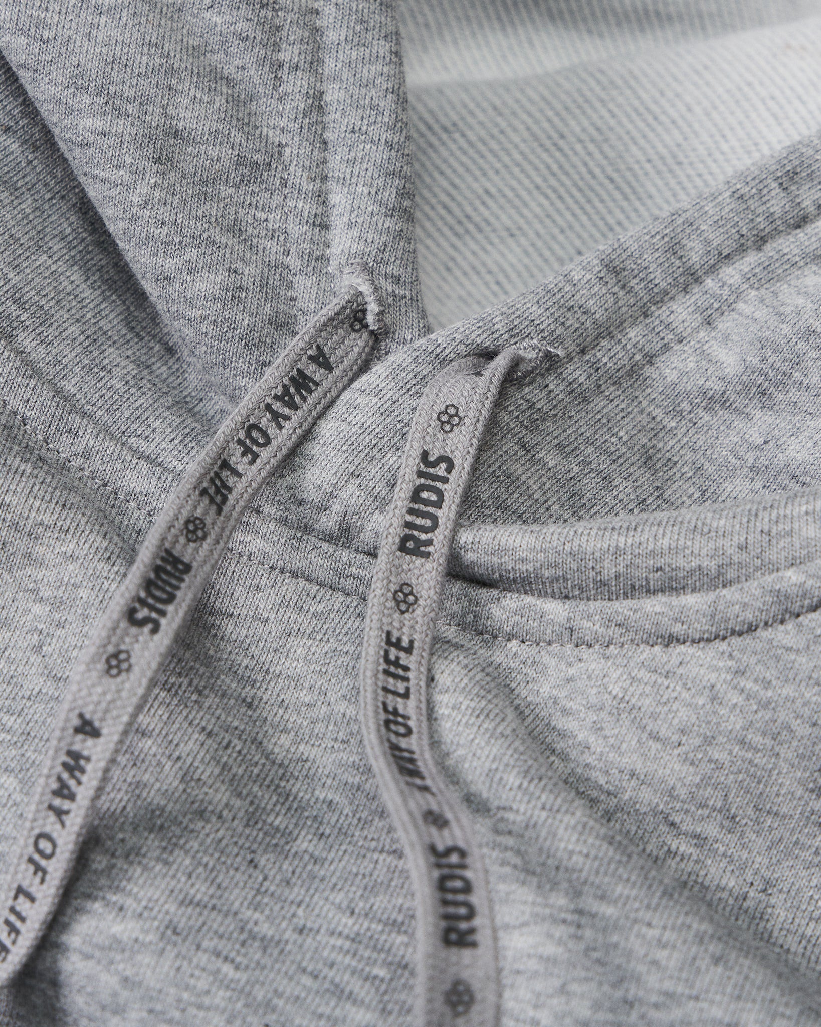 Close-up of gray fabric with 'Rudis' branding on a tag.
