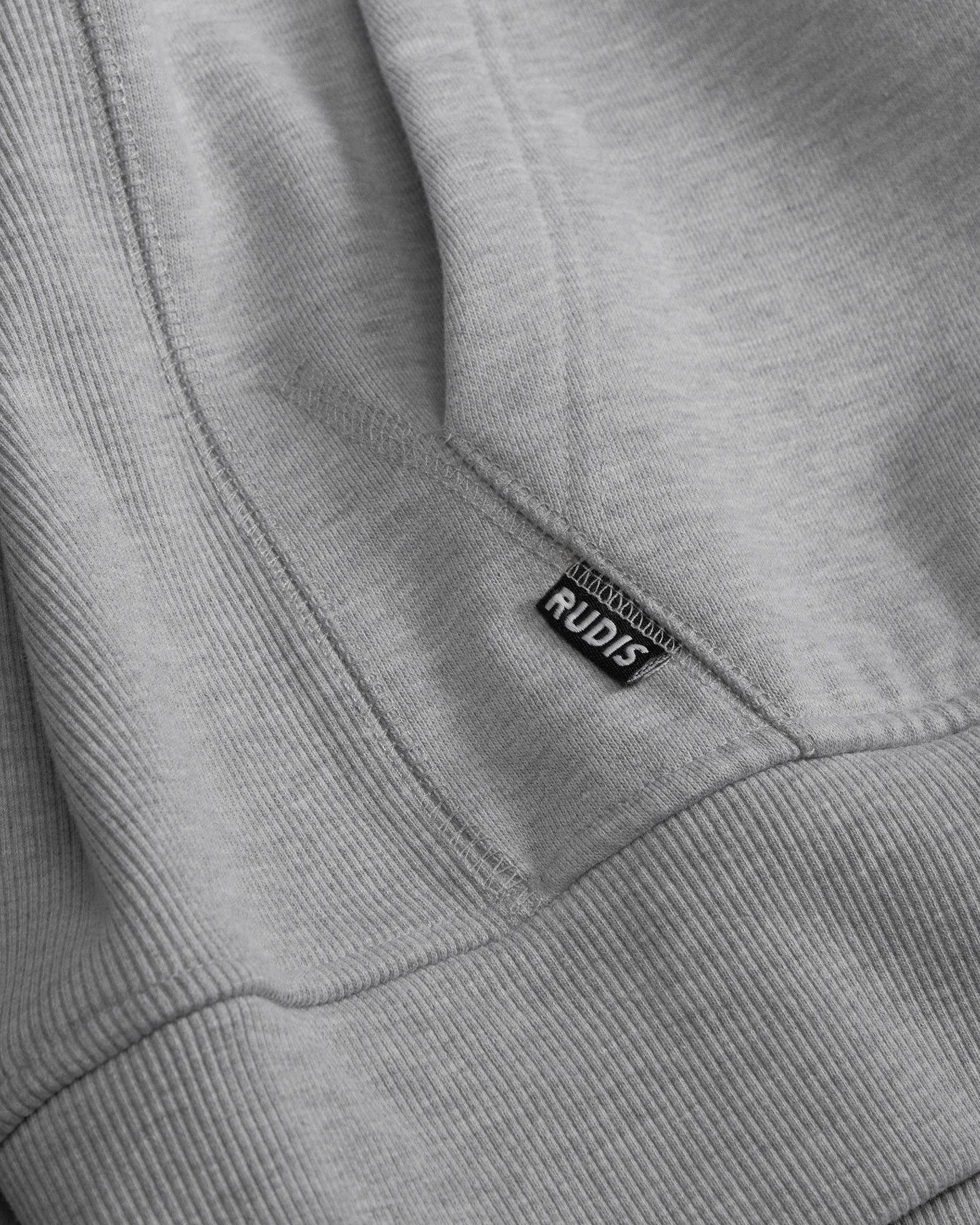 Close-up of a gray sweatshirt with a RUDIS label on the collar.