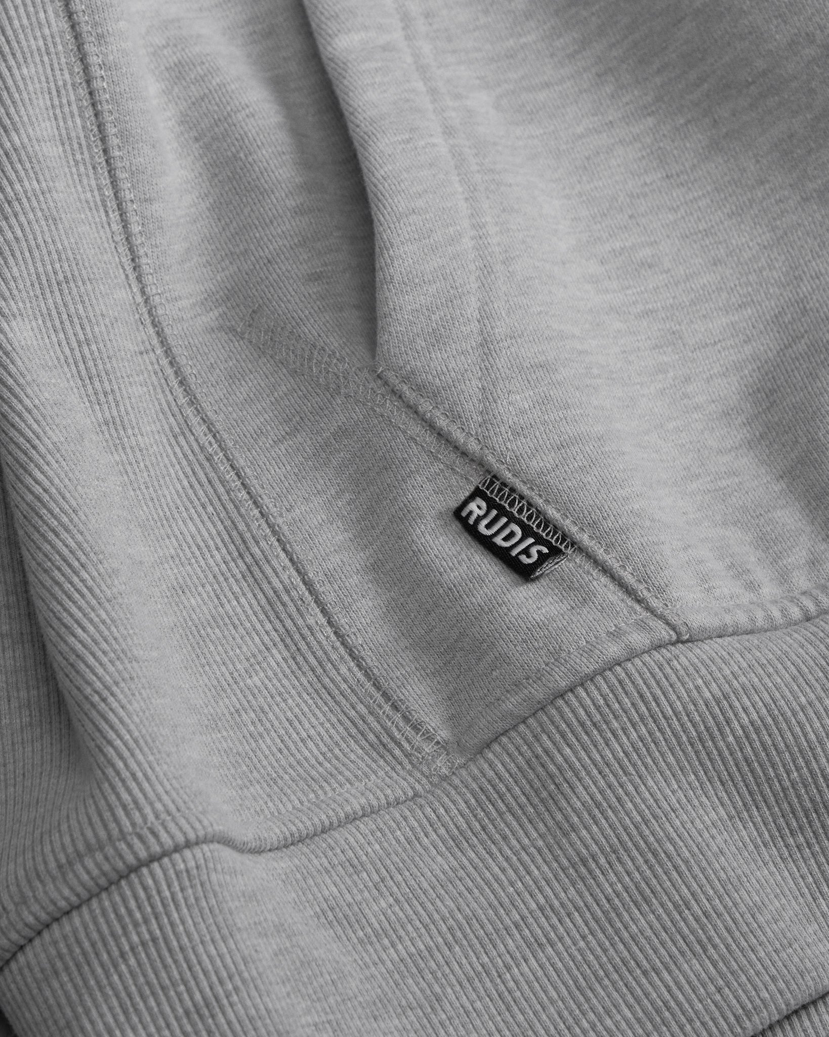 Close-up of a gray sweatshirt with a RUDIS label on the collar.