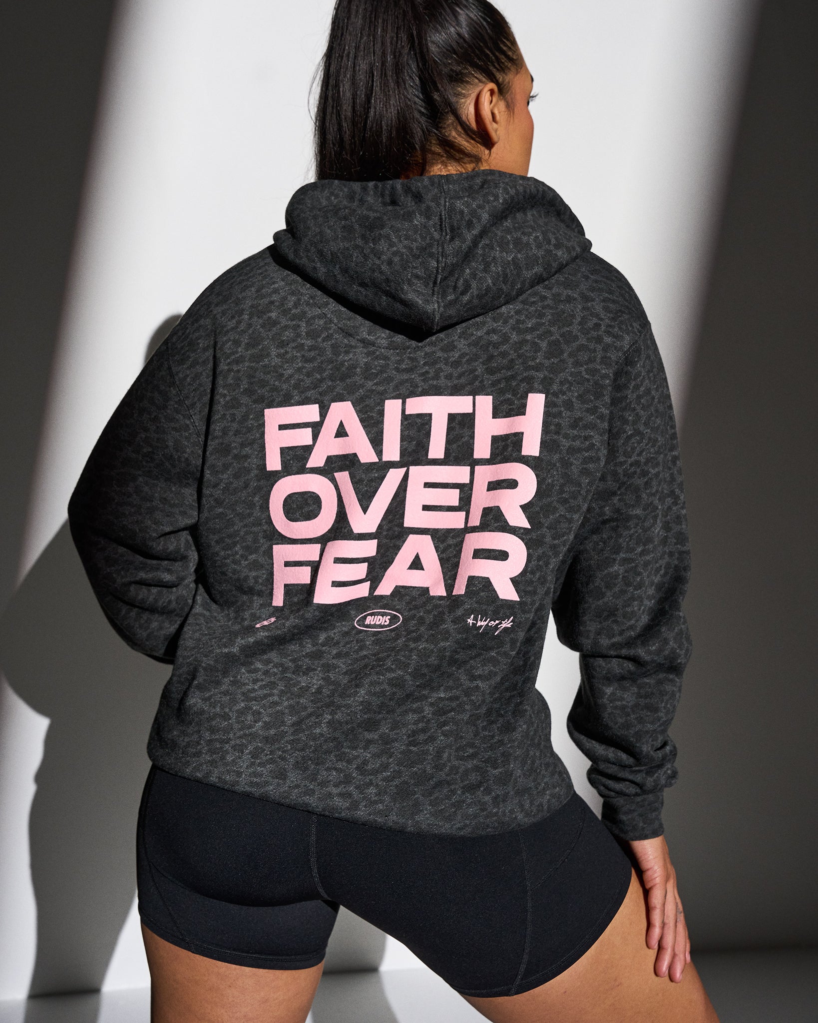Person wearing a animal print hoodie with 'Faith Over Fear' text on the back