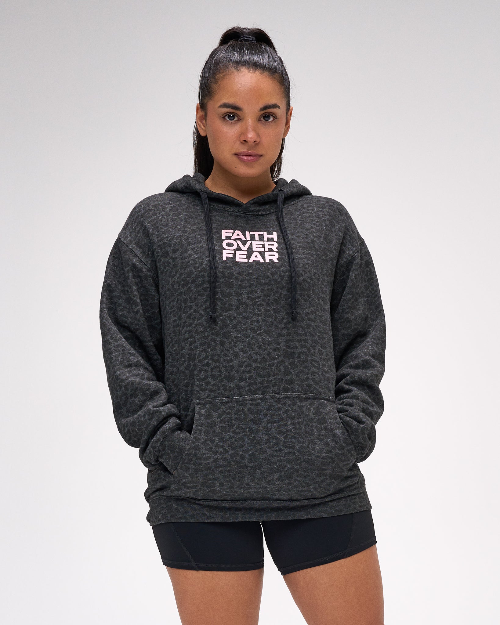 Person wearing a dark gray animal print hoodie with 'Faith Over Fear' text on a light gray background