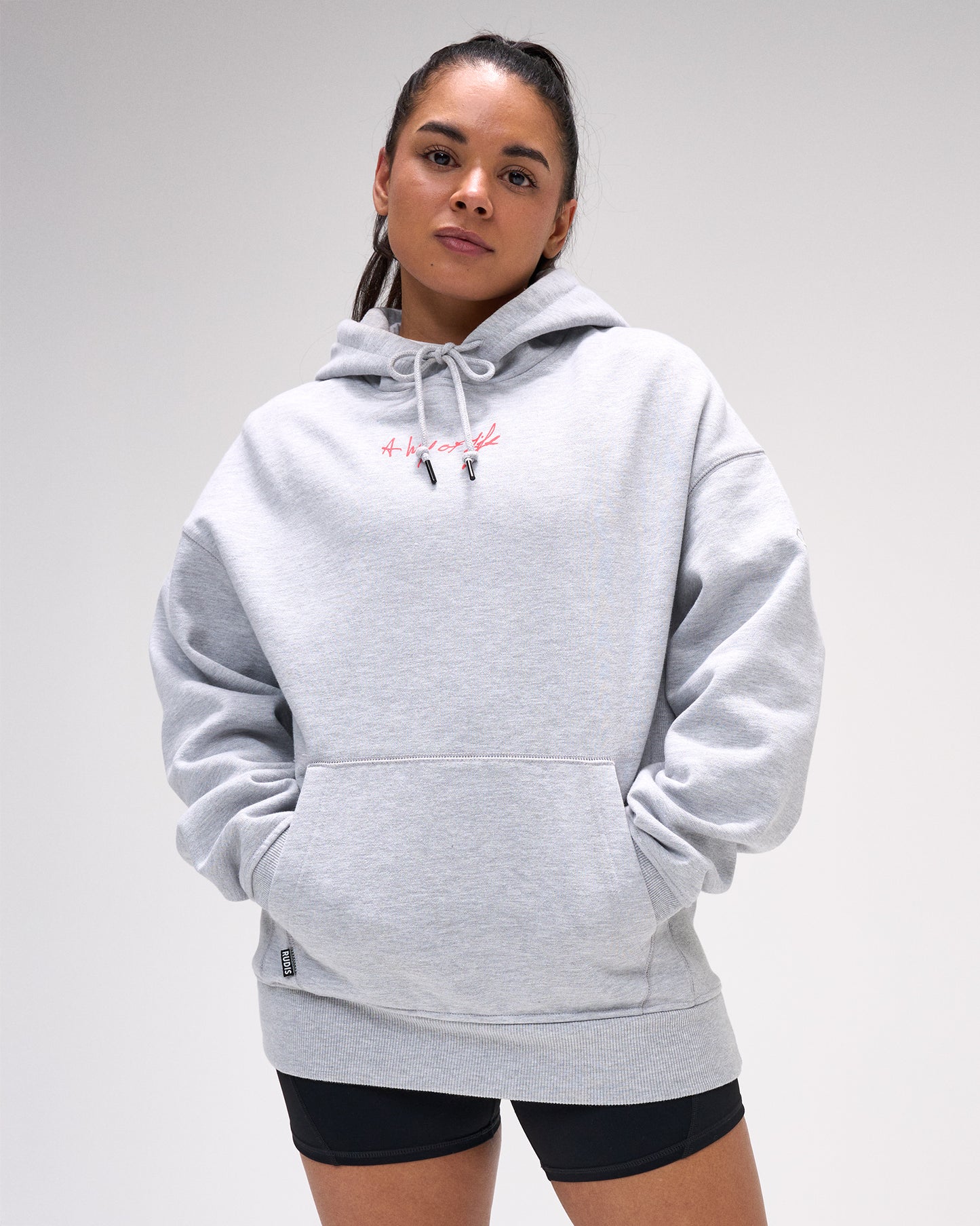 Woman wearing a gray hoodie with a brand logo on a white background