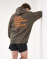 Person wearing a camouflage hoodie with orange 'For we wrestle not against flesh and blood' text on the back against a white background