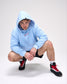 Person wearing a light blue hoodie and black sneakers with red accents on a white background