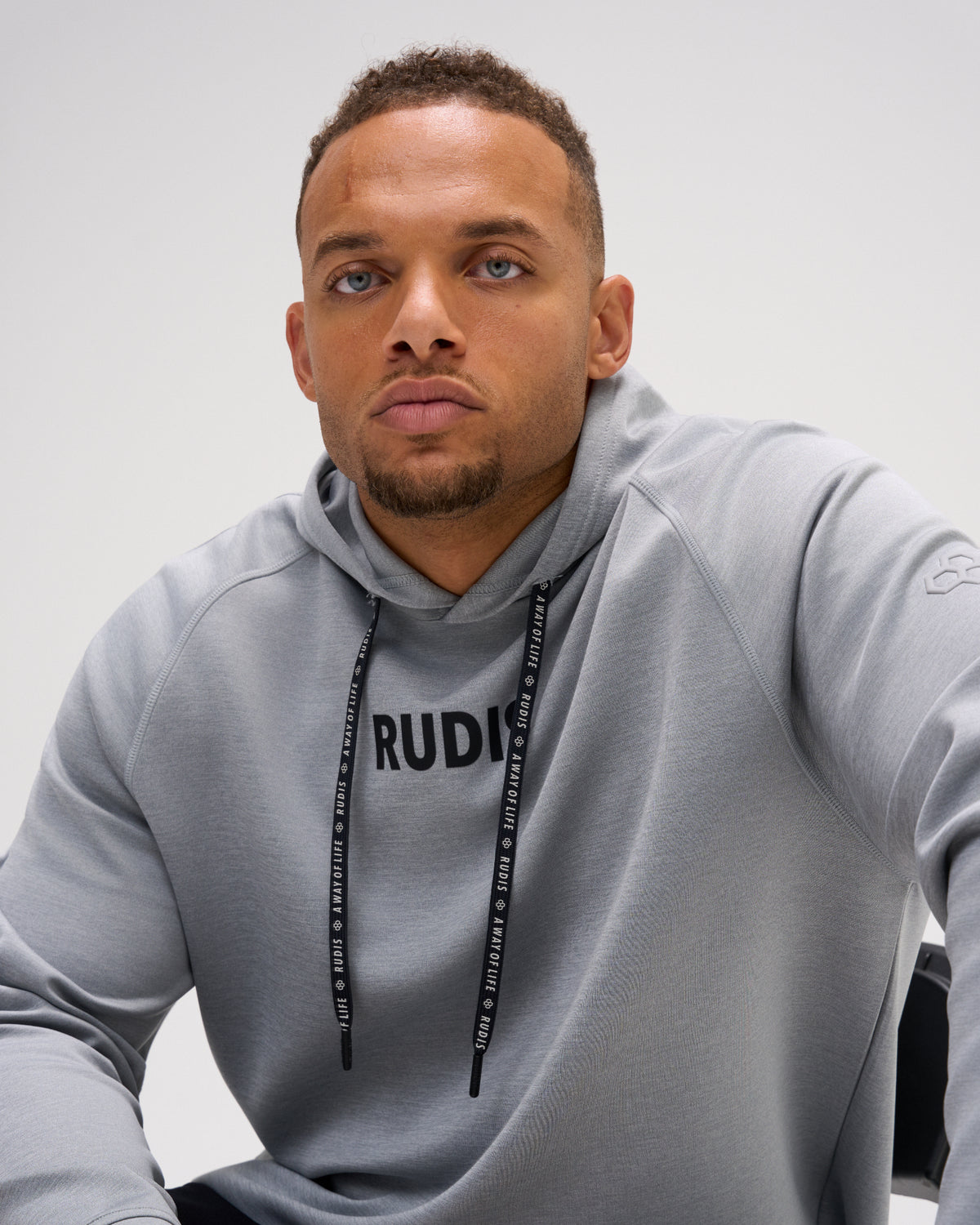 Model wearing the heather gray RUDIS Contrast COOL-FEEL Hoodie, highlighting the RUDIS chest graphic, branded drawcords, and raglan seams.