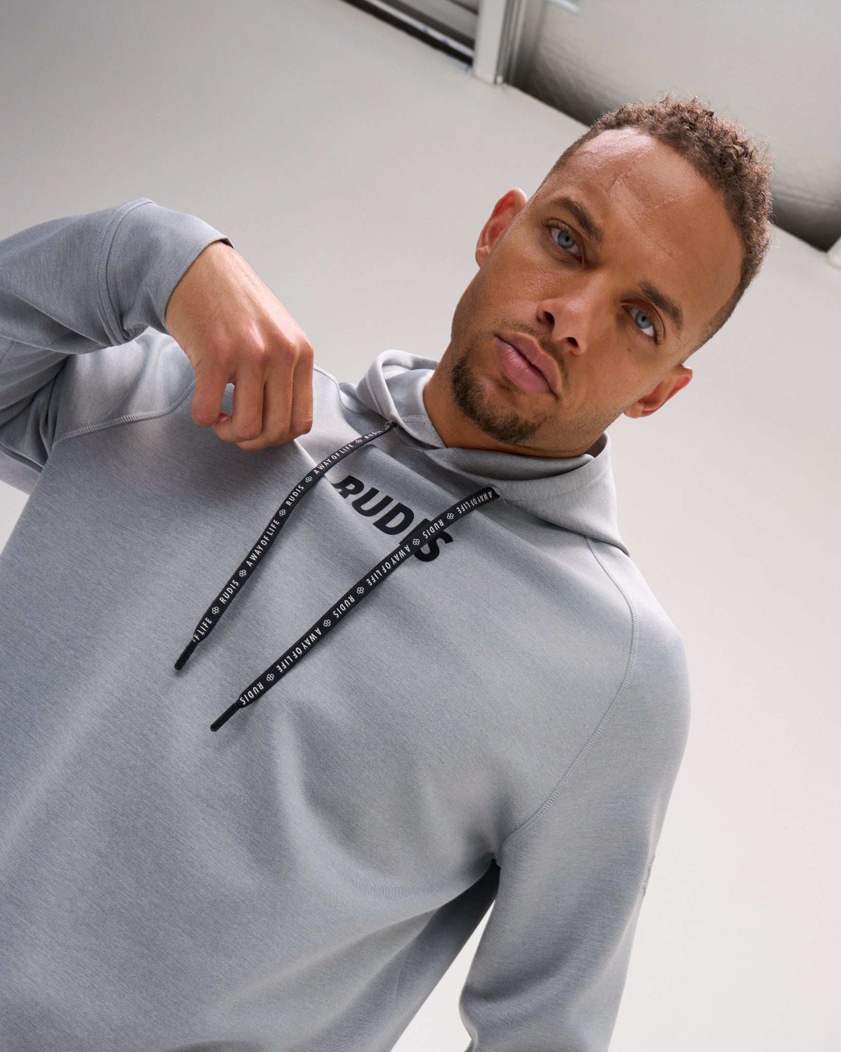 Close-up of the heather gray RUDIS Contrast COOL-FEEL Hoodie showing the RUDIS chest logo, branded drawcords, and performance fabric.