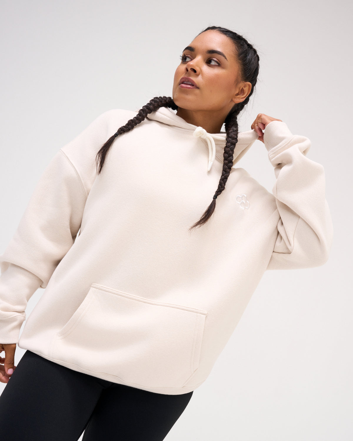 Female model wearing the Bone RUDIS Essential Hex Relaxed Comfort Fleece Hoodie, featuring a tonal embroidered logo and roomy kangaroo pocket.
