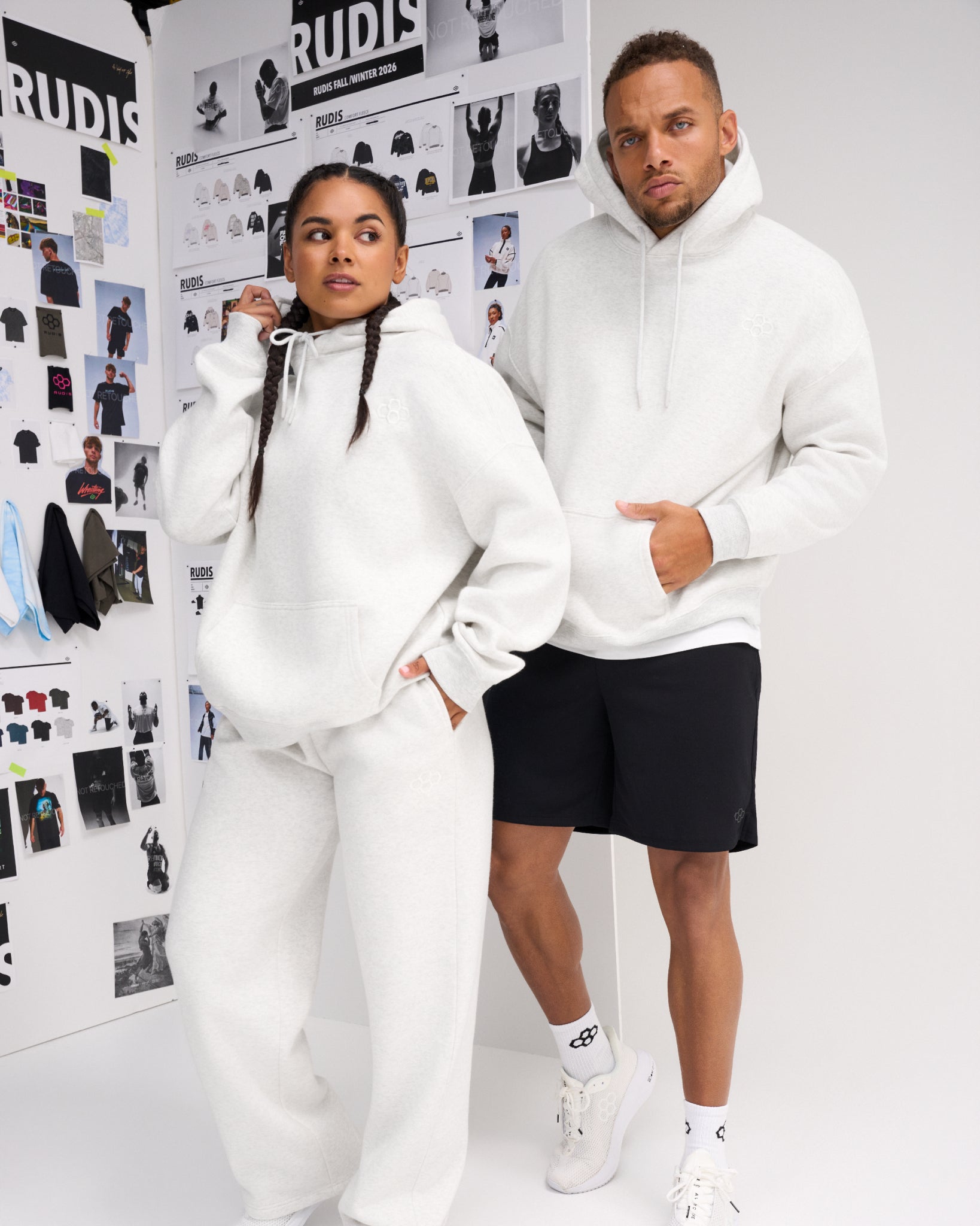 Male and female models wearing RUDIS Essential Hex Relaxed Comfort Fleece Hoodies in Heather Silver with tonal chest logos and matching athletic apparel.