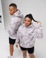 Male and female models wearing the RUDIS Essential Hex Relaxed Comfort Fleece Hoodie in Tree Camo, featuring woodland-inspired graphics and Hex chest logos.