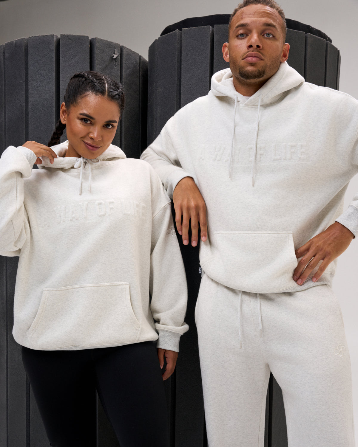 Male and female models wearing the RUDIS A Way Of Life Relaxed Comfort Fleece Hoodie in Heather Silver, highlighting tonal A Way Of Life lettering and kangaroo pockets.