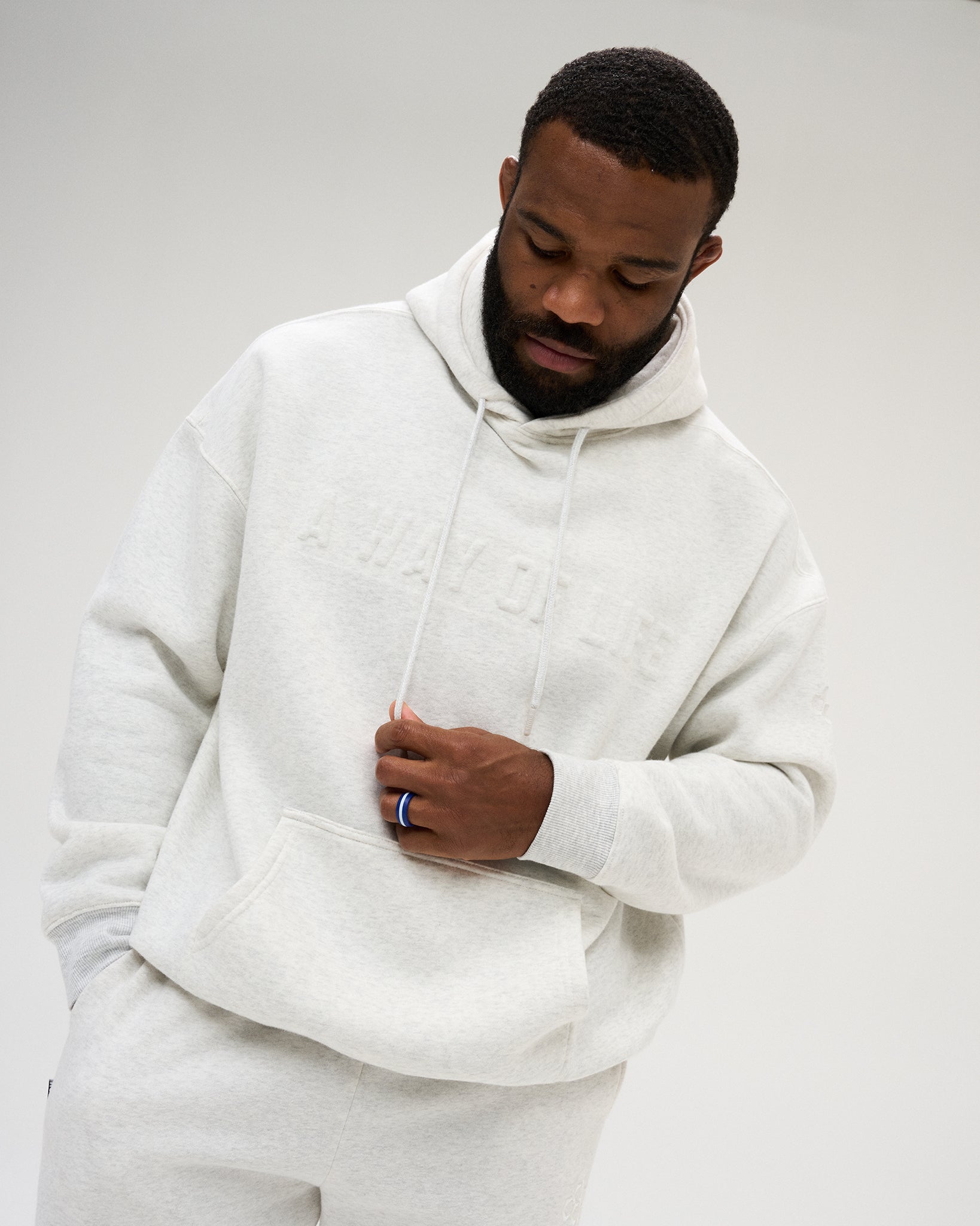 Front view of a male model wearing the RUDIS A Way Of Life Relaxed Comfort Fleece Hoodie in Heather Silver, showing tonal chest lettering, ribbed cuffs and relaxed fit.