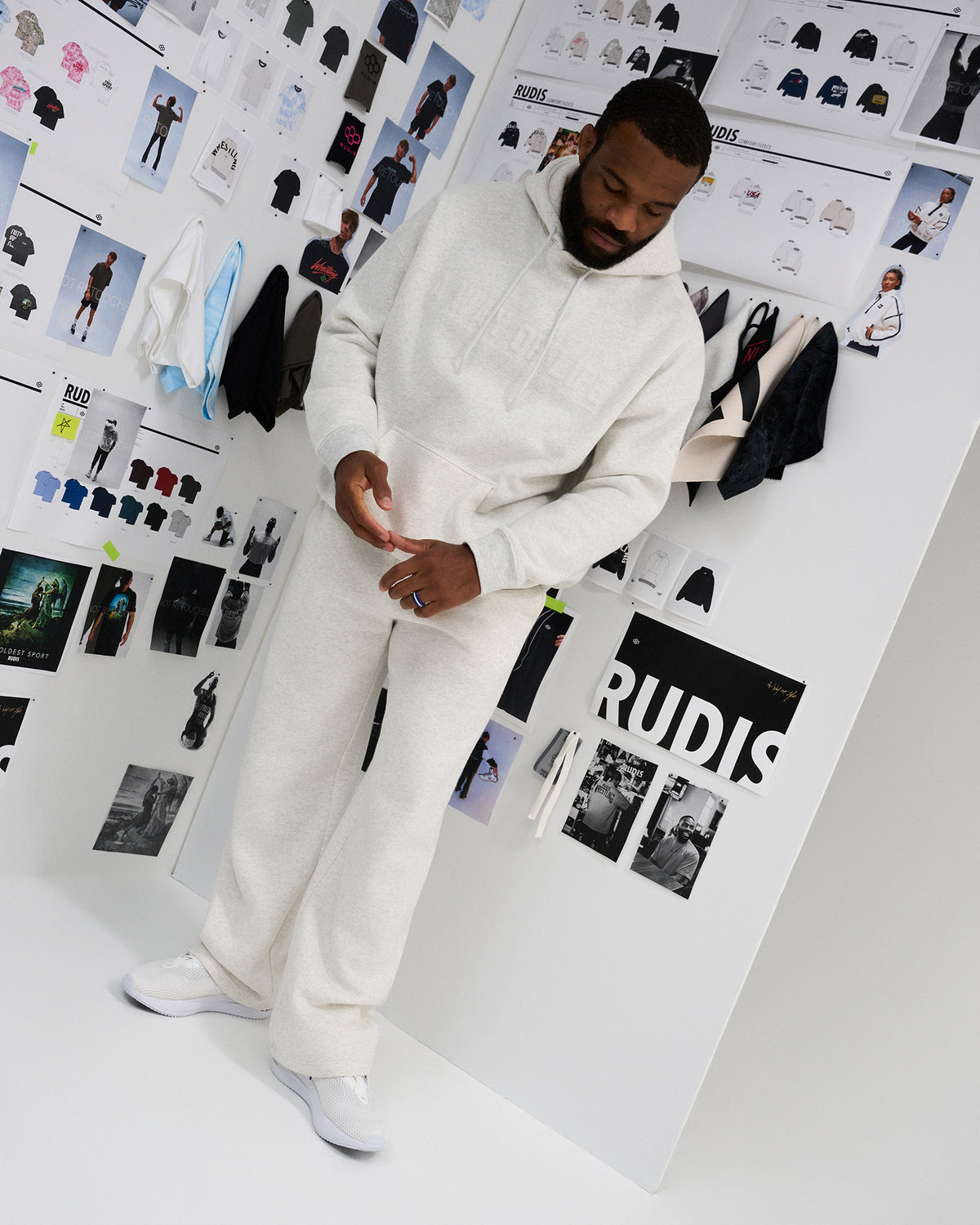 Full-body lifestyle view of a male model in the RUDIS A Way Of Life Relaxed Comfort Fleece Hoodie in Heather Silver with matching sweatpants and white sneakers.