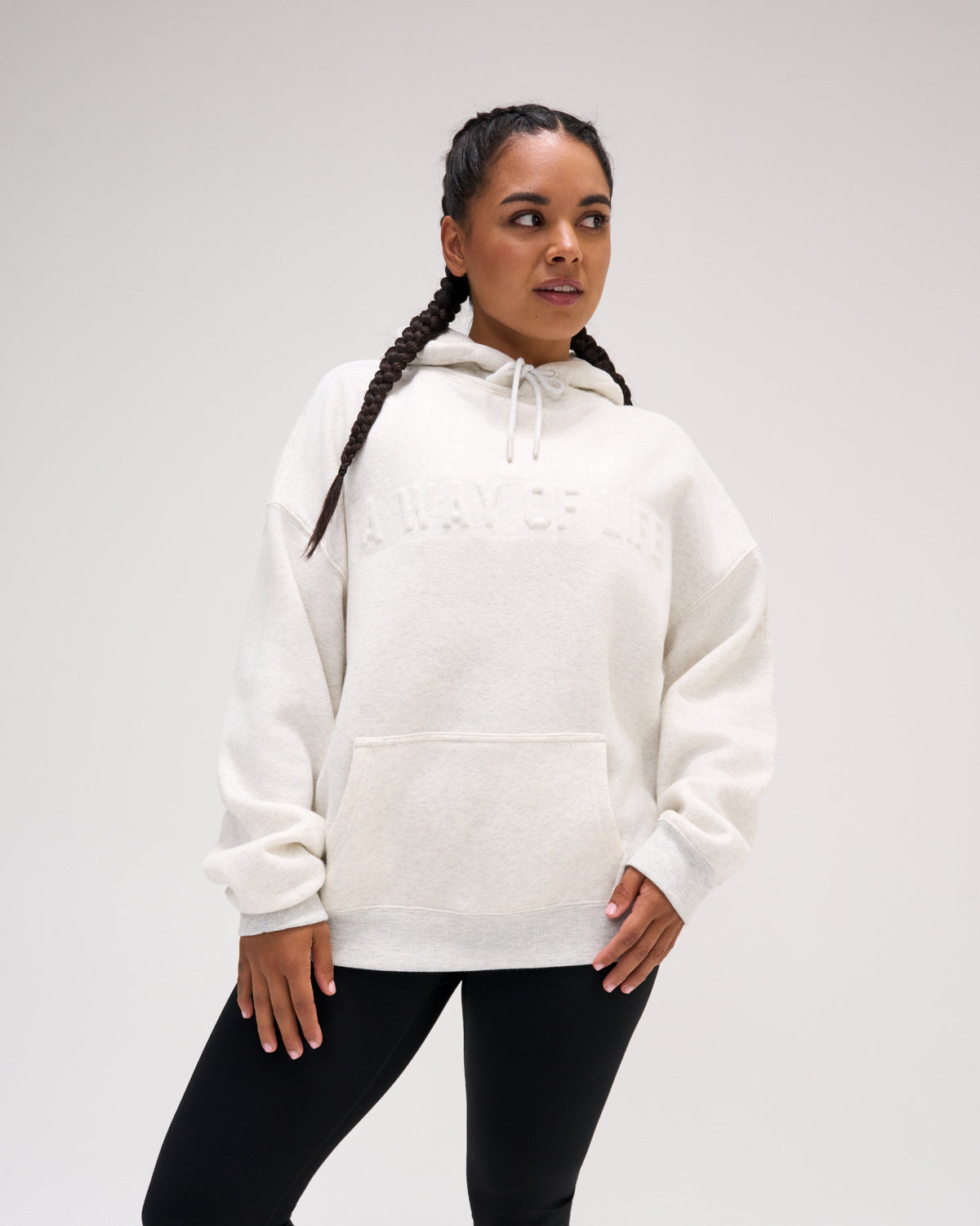 Female model wearing the RUDIS A Way Of Life Relaxed Comfort Fleece Hoodie in Heather Silver with tonal chest lettering, dropped shoulders, ribbed cuffs and kangaroo pocket.