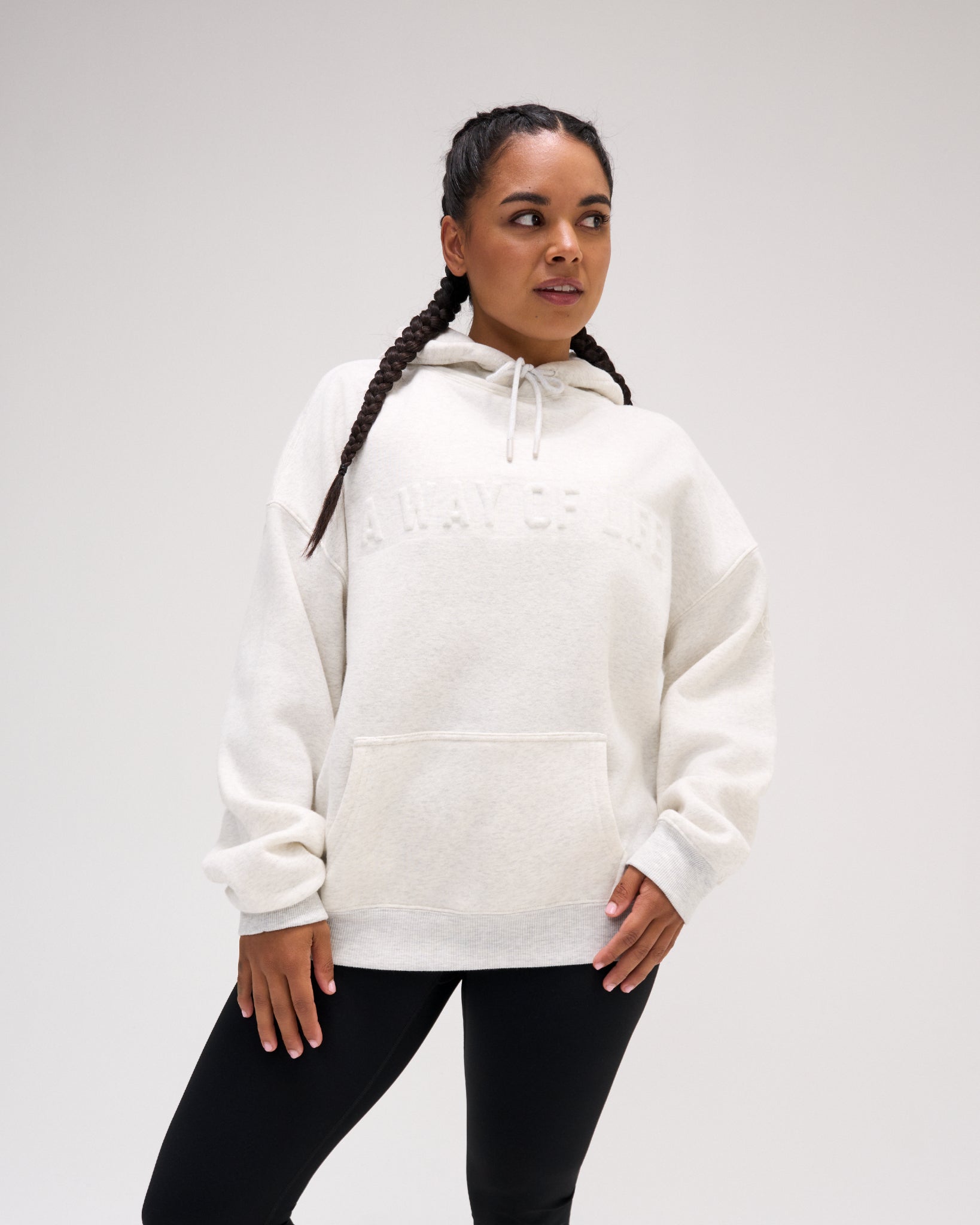 Female model wearing the RUDIS A Way Of Life Relaxed Comfort Fleece Hoodie in Heather Silver with tonal chest lettering, dropped shoulders, ribbed cuffs and kangaroo pocket.