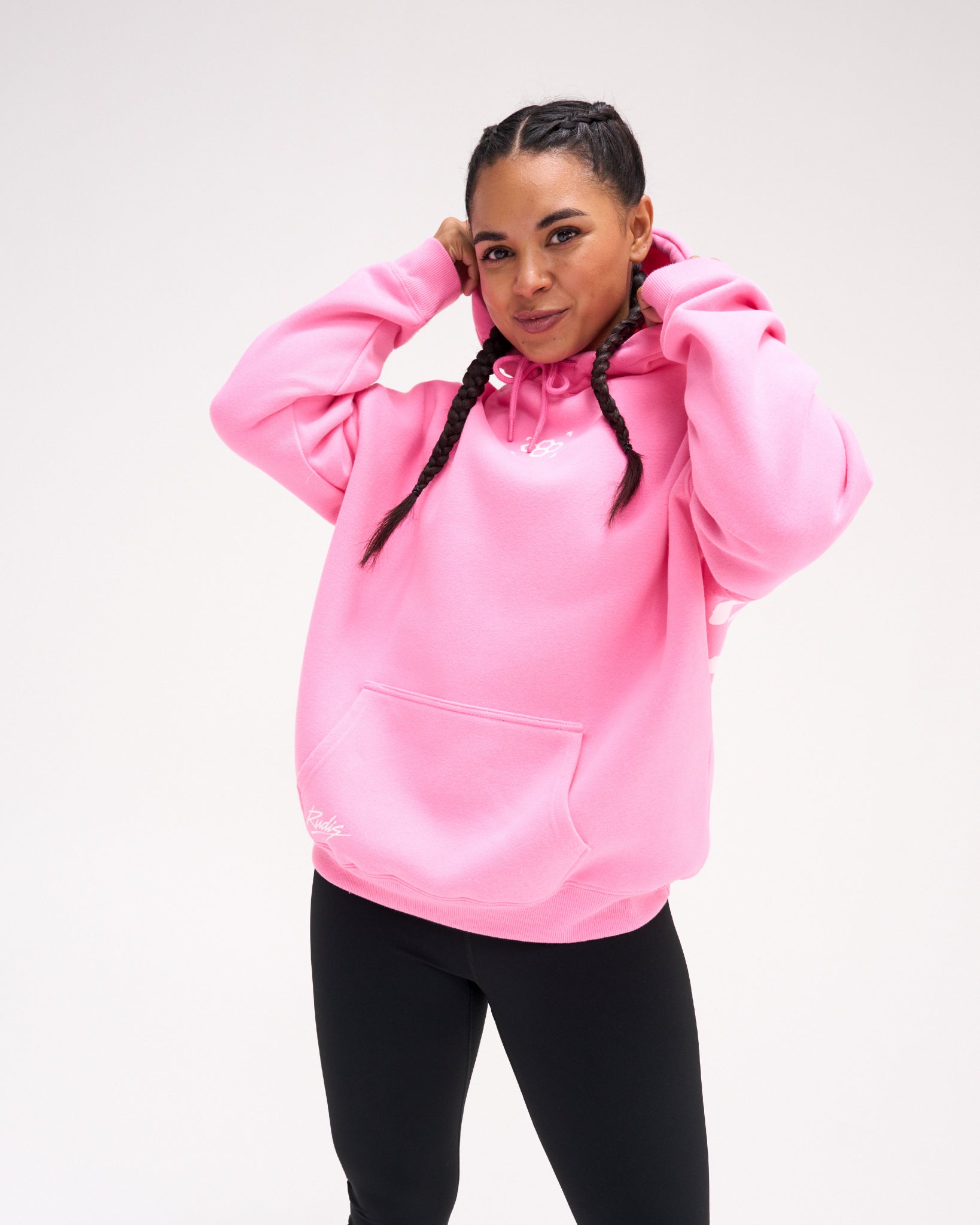 Female model wearing the RUDIS Art of Wrestling Relaxed Comfort Fleece Hoodie in Bubble Gum Pink, showing the relaxed fit, small white chest logo, drawstring hood and front kangaroo pocket.
