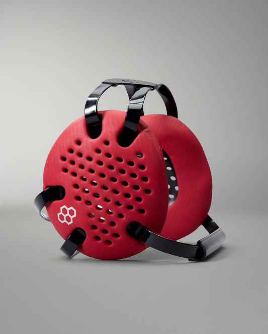 Angled view of RUDIS Elite Airflow Wrestling Headgear in Red Carbon, featuring ventilated ear guards with a carbon-fiber pattern, black adjustable straps and white RUDIS logo.