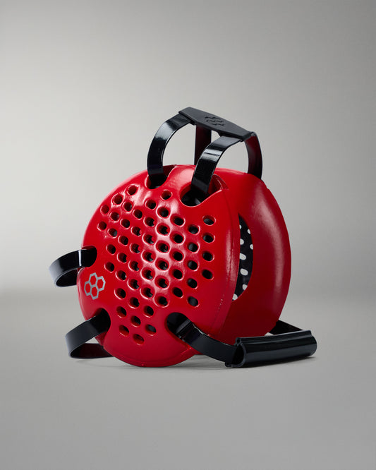 Red wrestling headgear with black handle and straps on a gray background