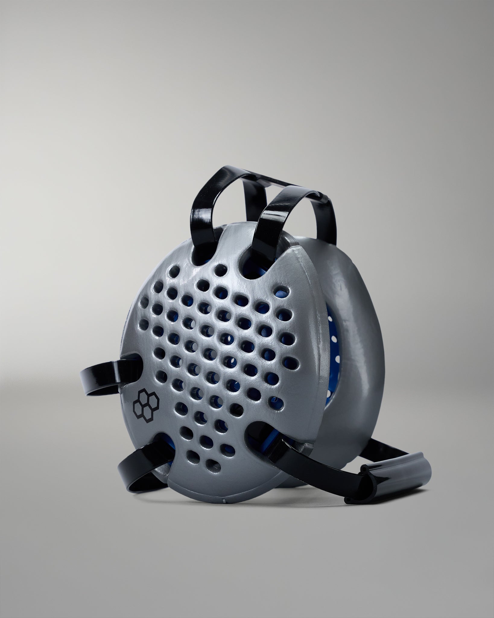 Gray wrestling headgear with black straps on a gray background
