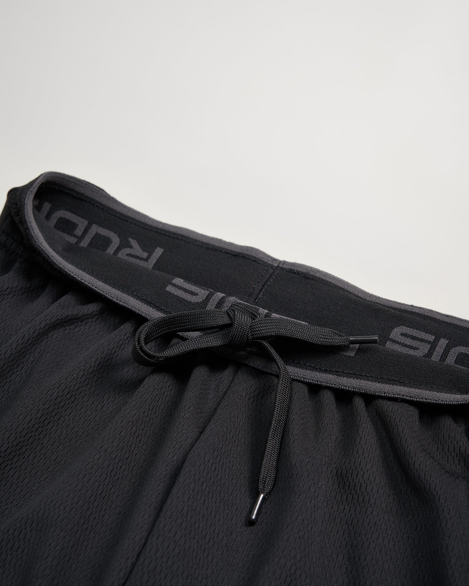 A close-up view of a black athletic short featuring a drawstring and a textured waistband