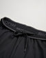A close-up view of a black athletic short featuring a drawstring and a textured waistband