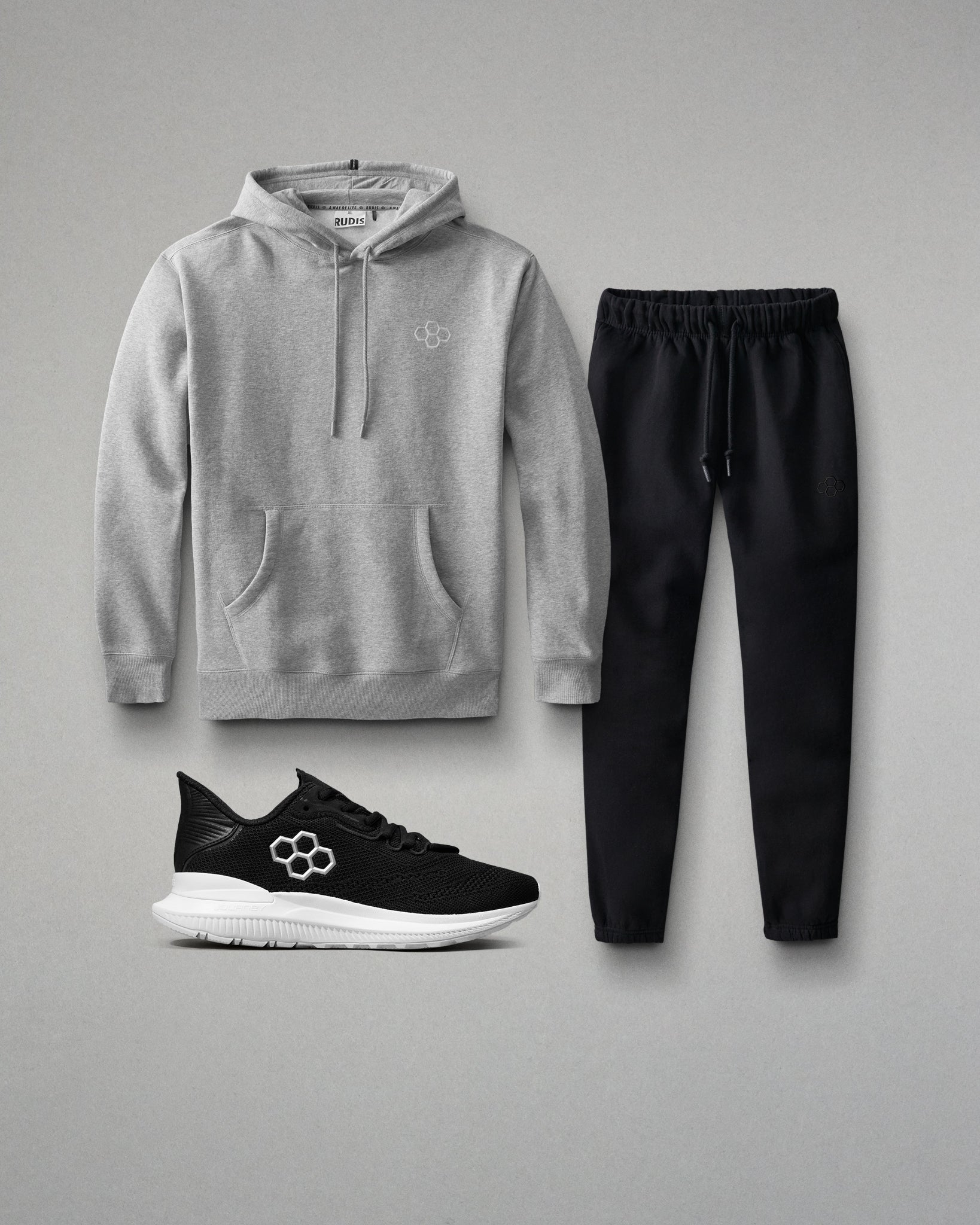 Gray hoodie, black pants, and black sneakers on a gray background