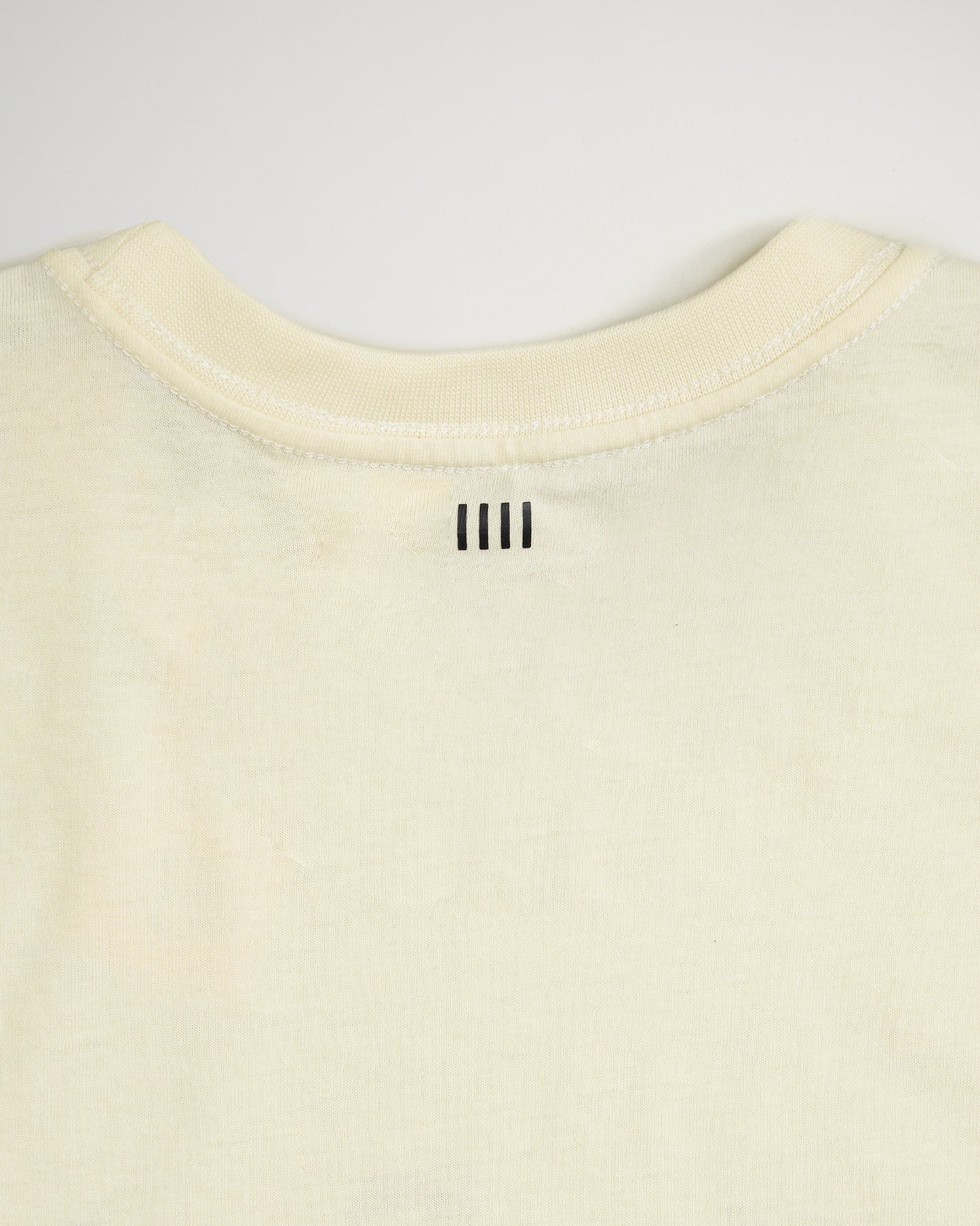 A close-up view of the back neckline of a light-colored shirt featuring three vertical black lines stitched at the center