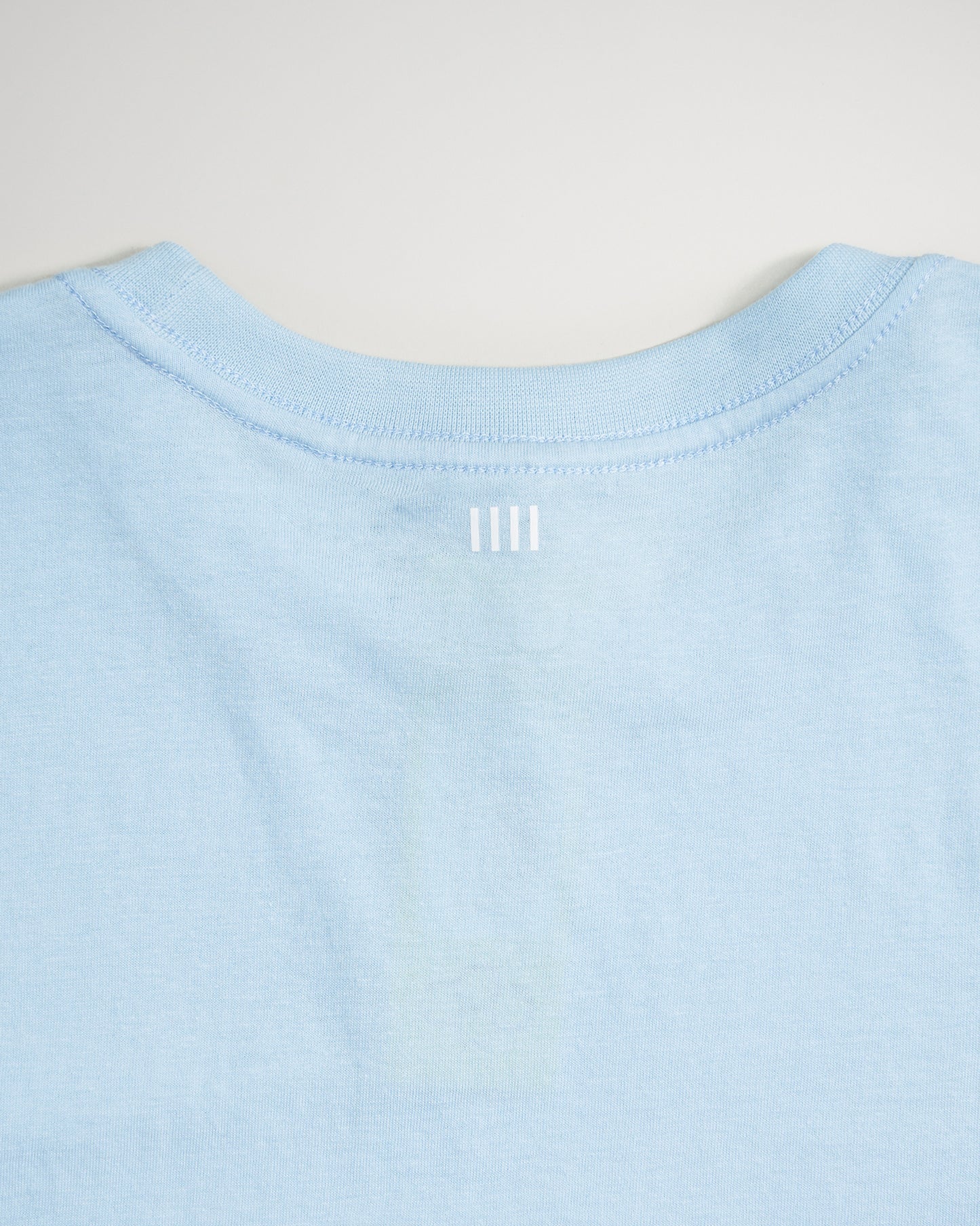 A light blue t-shirt showcases a simple design with white horizontal lines at the back neck area