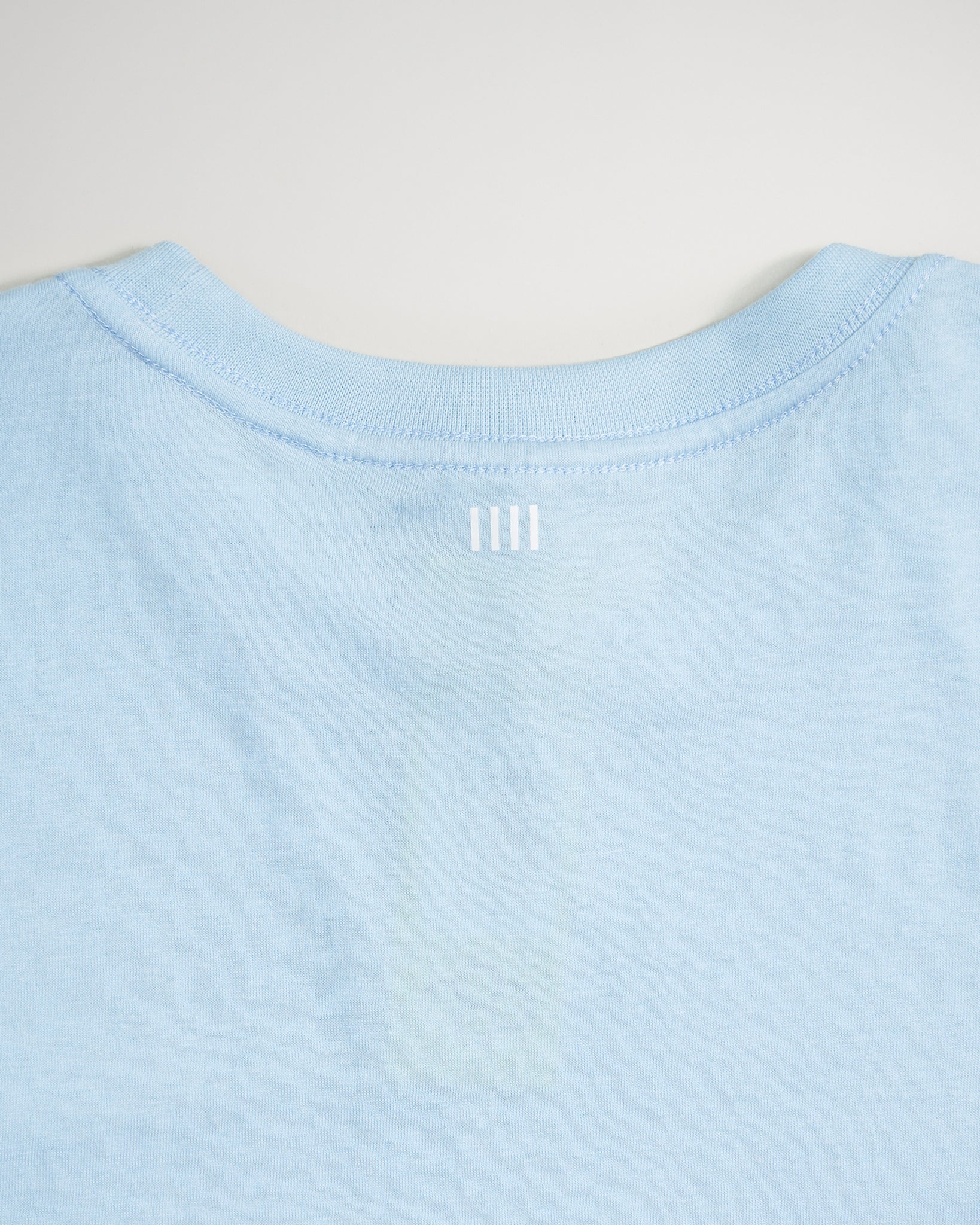 A light blue t-shirt showcases a simple design with white horizontal lines at the back neck area