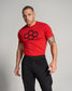 A fit man wearing a red t-shirt with a black graphic design and black athletic pants poses confidently against a light gray background