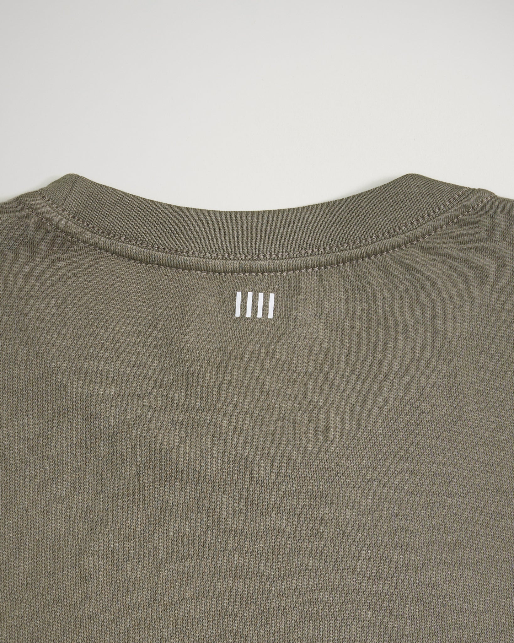 A close-up view of the back neckline of an olive green shirt featuring three vertical white lines as a design element
