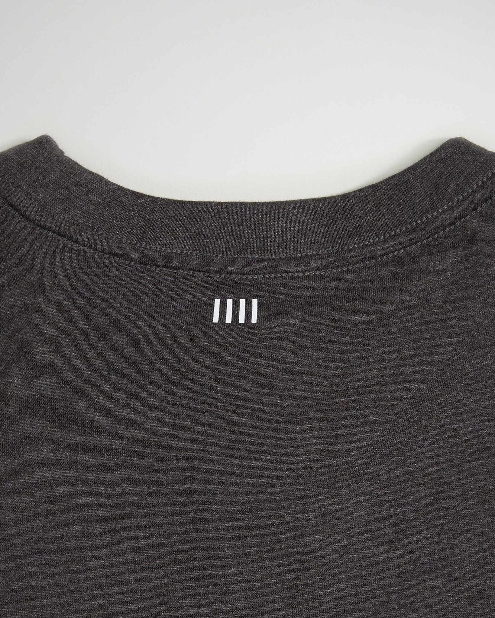 This image showcases the back neckline of a dark gray t-shirt featuring a subtle white logo design