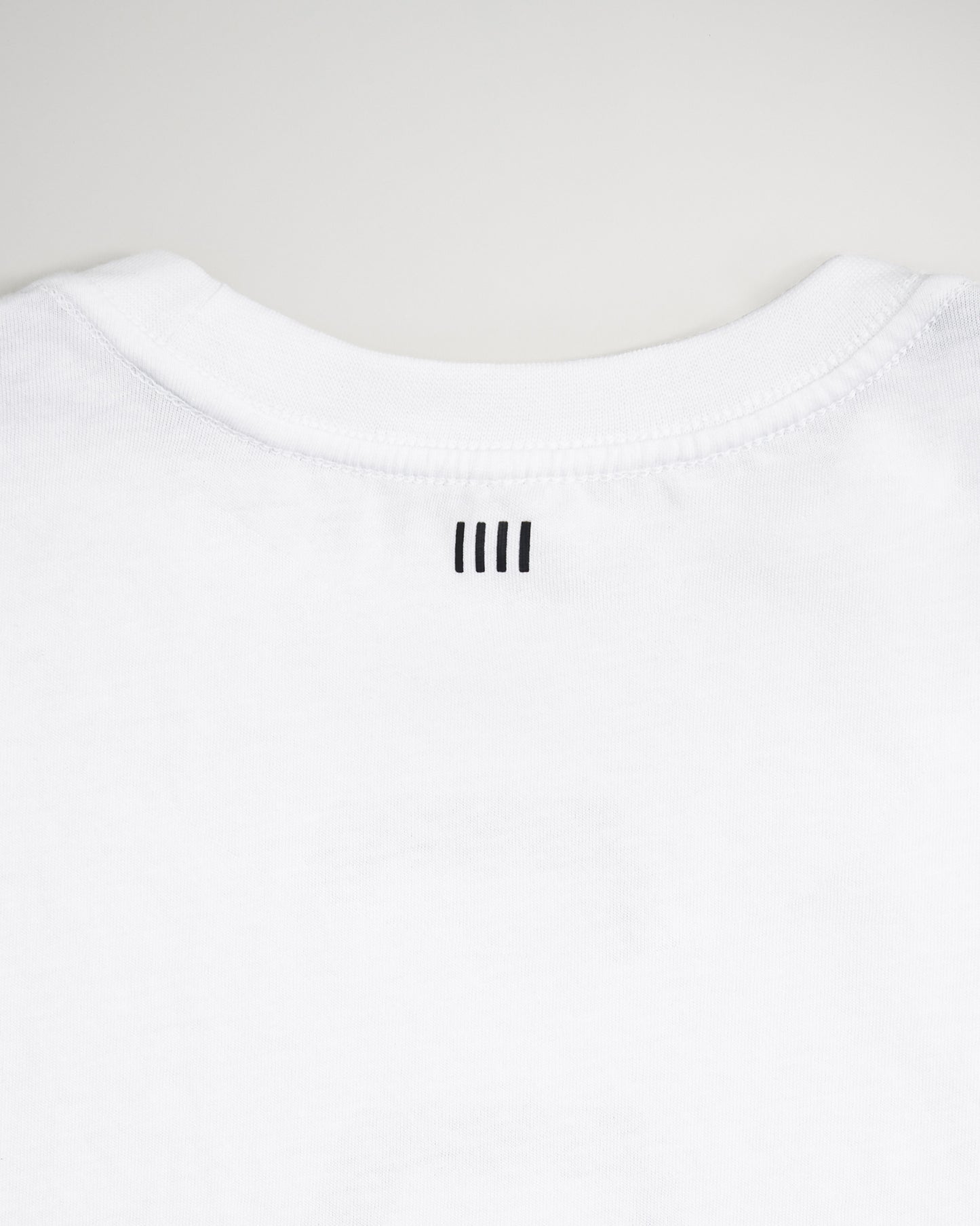 A close-up view of the back neckline of a white t-shirt featuring three vertical black lines above the collar