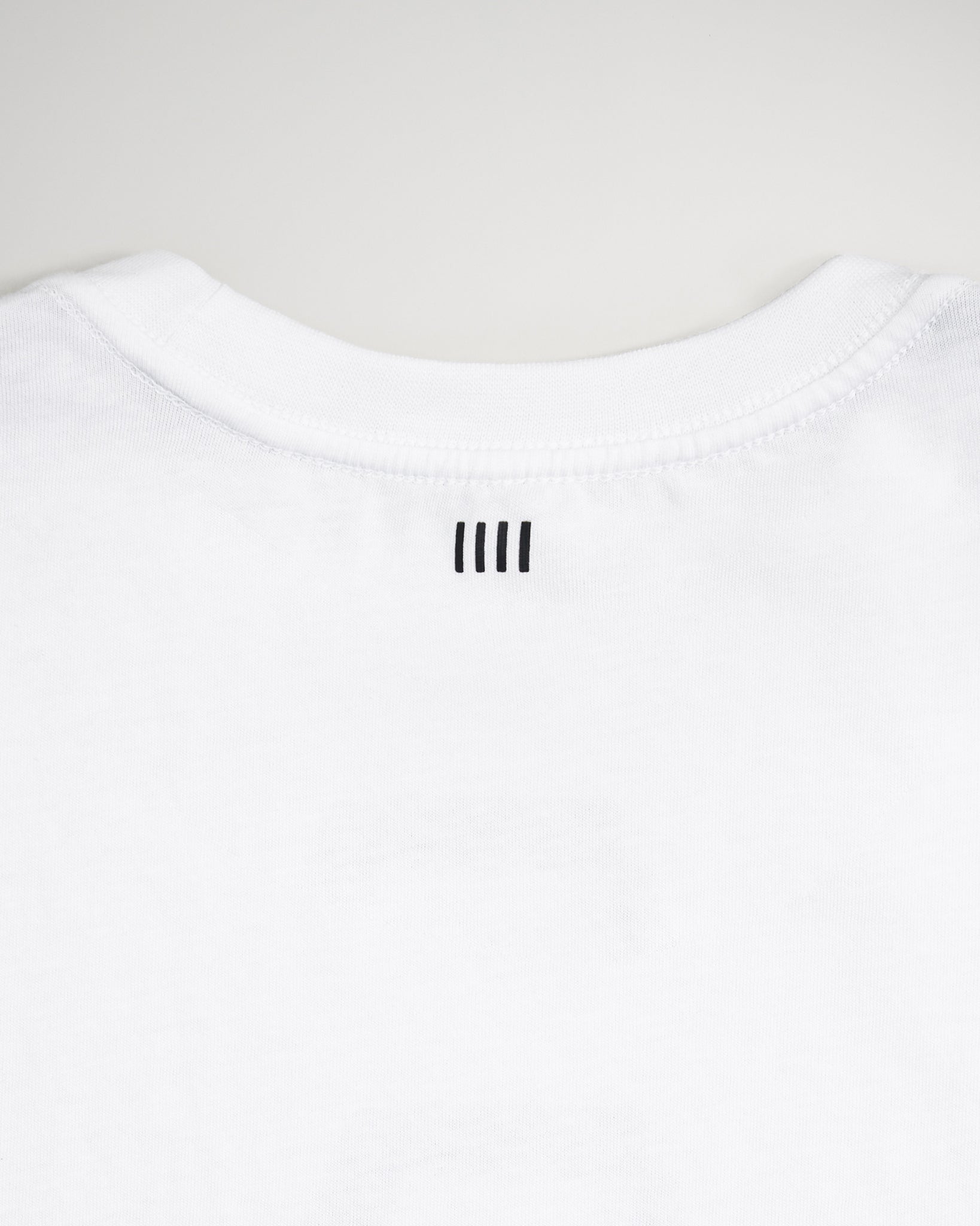 A close-up view of the back neckline of a white t-shirt featuring three vertical black lines above the collar