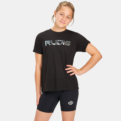 A young girl stands confidently in a black t-shirt with RUDIS printed on it paired with black shorts featuring a logo showcasing a casual athletic look