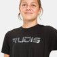 A young person wearing a black t-shirt featuring the shiny logo RUDIS across the chest smiling confidently against a neutral background