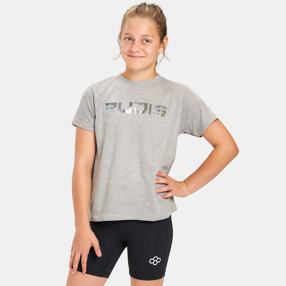 A young girl poses confidently in a light gray athletic t-shirt with a shiny print and black compression shorts showcasing a sporty look