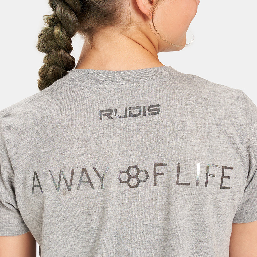 A young woman wearing a light gray t-shirt displaying the words RUDIS and A WAY OF LIFE on the back with a braided hairstyle