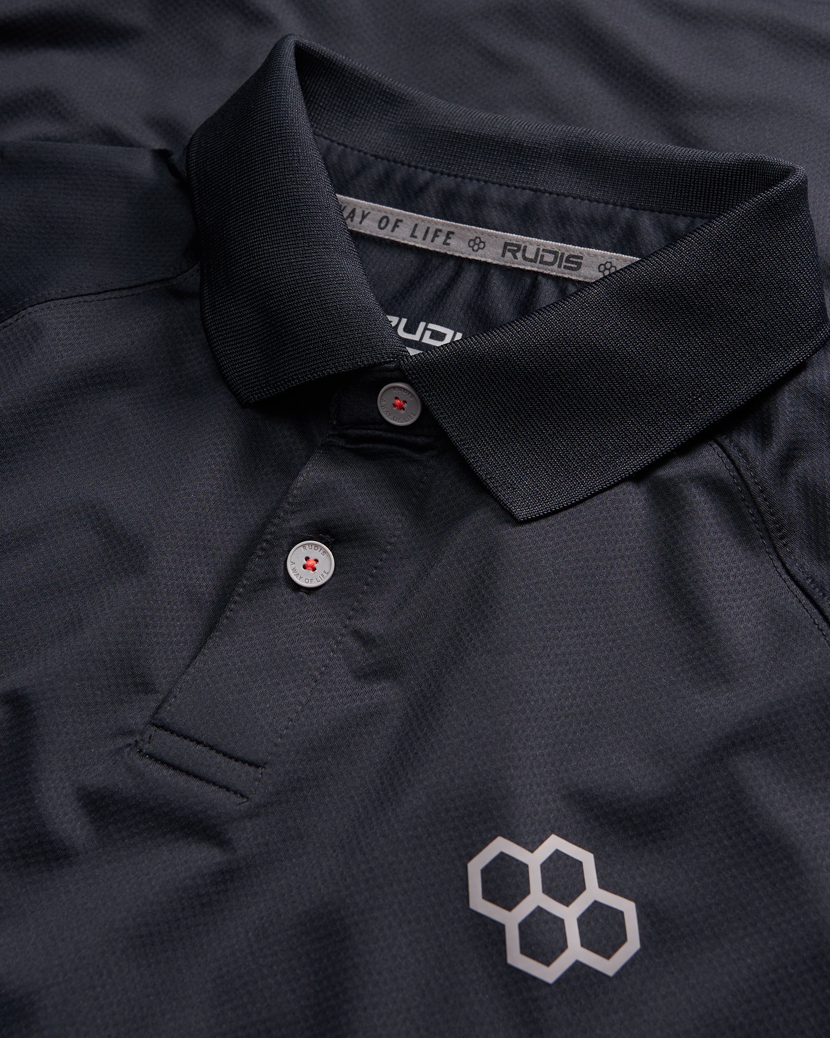 A close-up view of a black polo shirt featuring a classic collar two buttons and a geometric logo in a contrasting shade