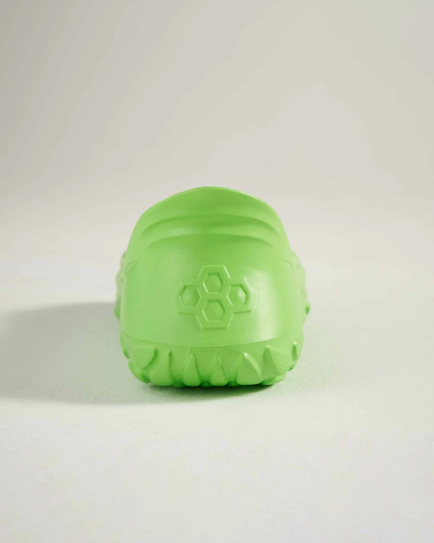 A rear view of a bright green shoe with a textured sole and hexagonal design on the side showcasing its unique style and design elements
