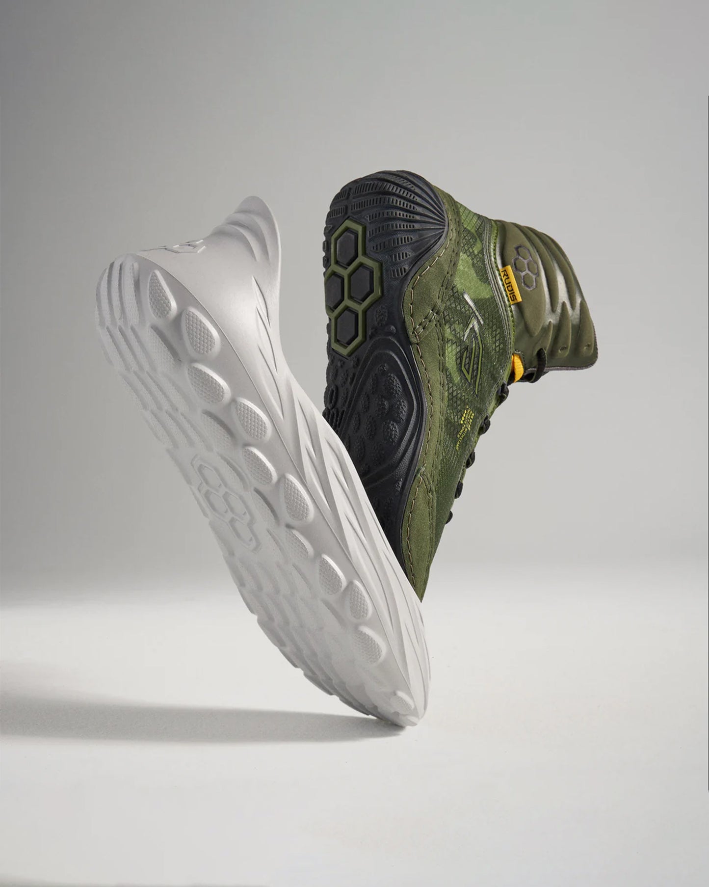 This image depicts two contrasting athletic shoes one in white and the other in dark green showcasing their unique designs and tread patterns